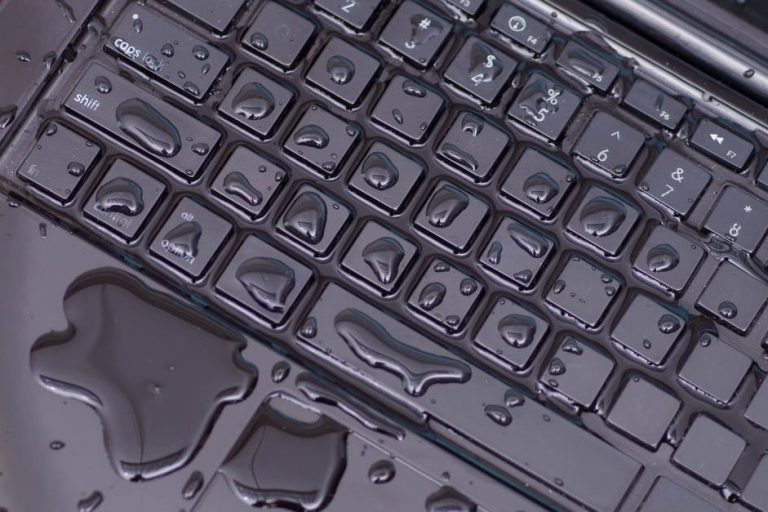 Wet laptop keyboard with water droplets and spills.