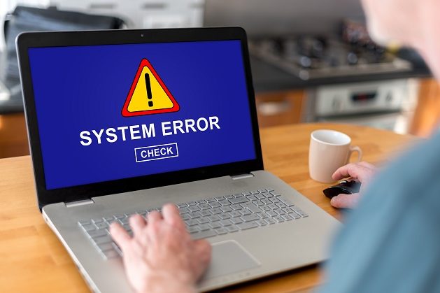 Person using a laptop displaying a "System Error" warning on the screen.