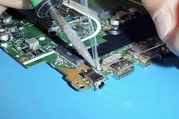 Close-up of a hand repairing a circuit board with a soldering iron.